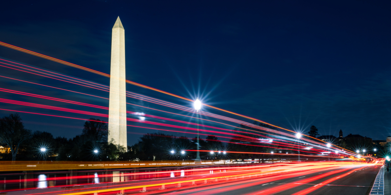 The Washington Monument as scene from Independence Avenue. light trails created by oncoming traffic create a dazzling night photograph.