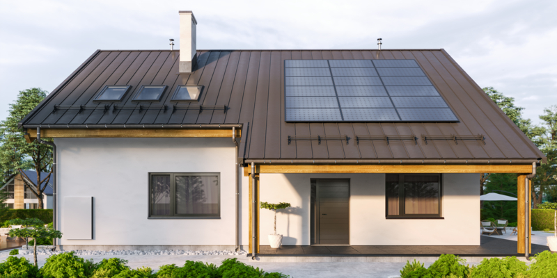Modern house with solar panels and wall battery for energy storage.
