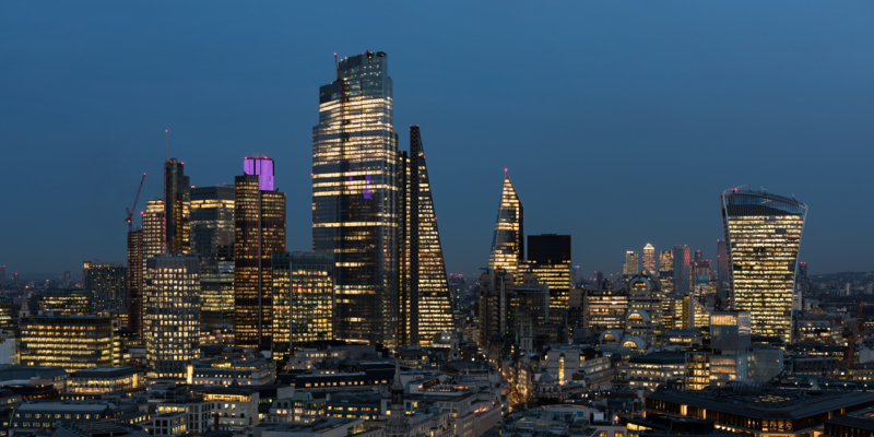 An elevated view of the City of London’s illuminated financial district skyline at night.