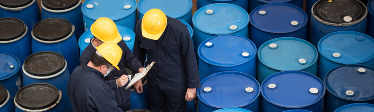 Group of men working at a chemical warehouse classifying barrels